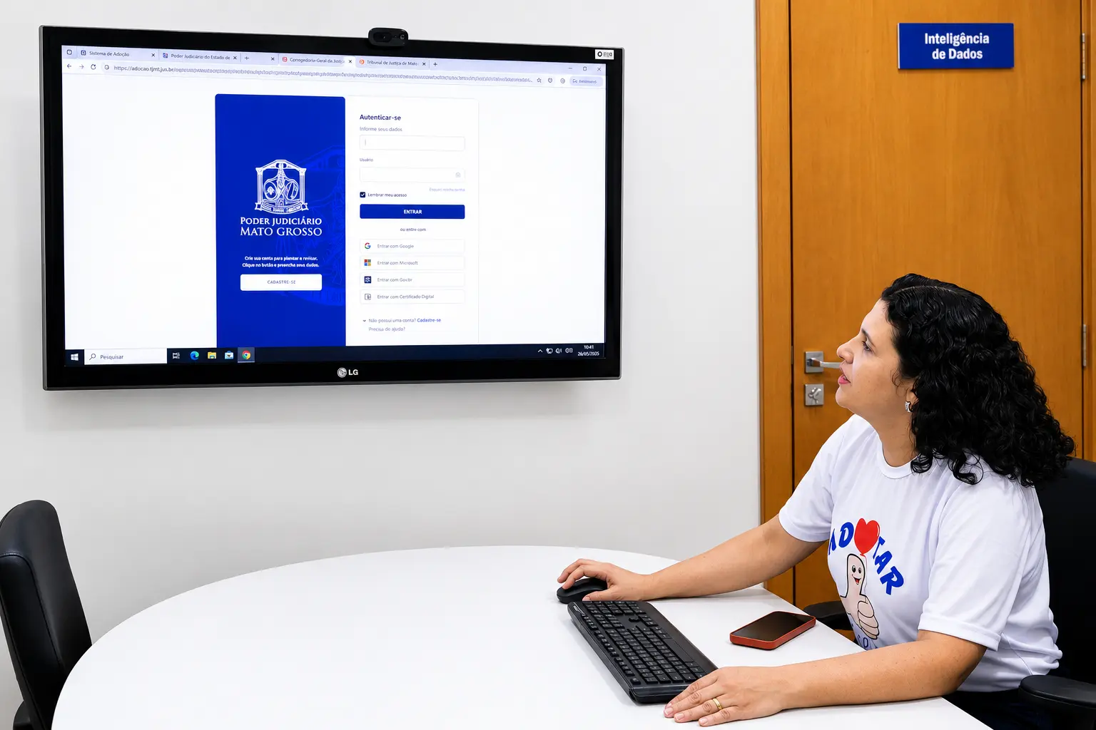 A secretaria da Ceja está sentada em sala da área de Inteligência de Dados e mostra o novo sistema virtual de adoção.