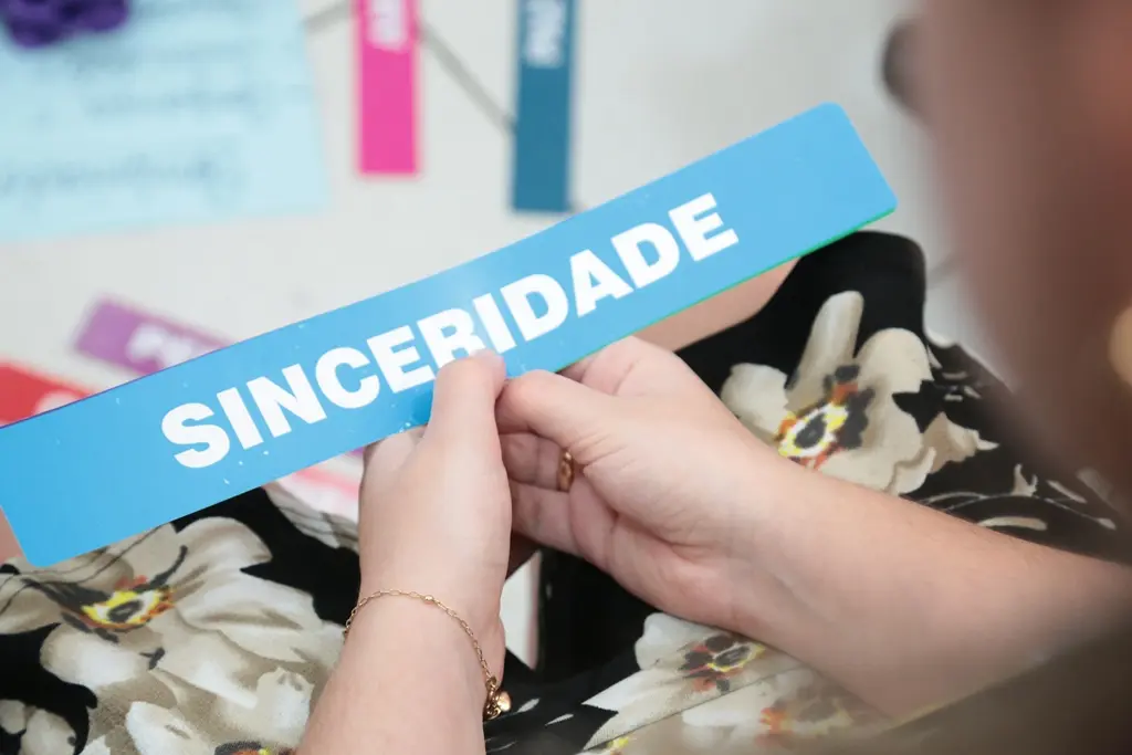 Visão aproximada das mãos de uma mulher segurando uma placa azul-clara com a palavra 
