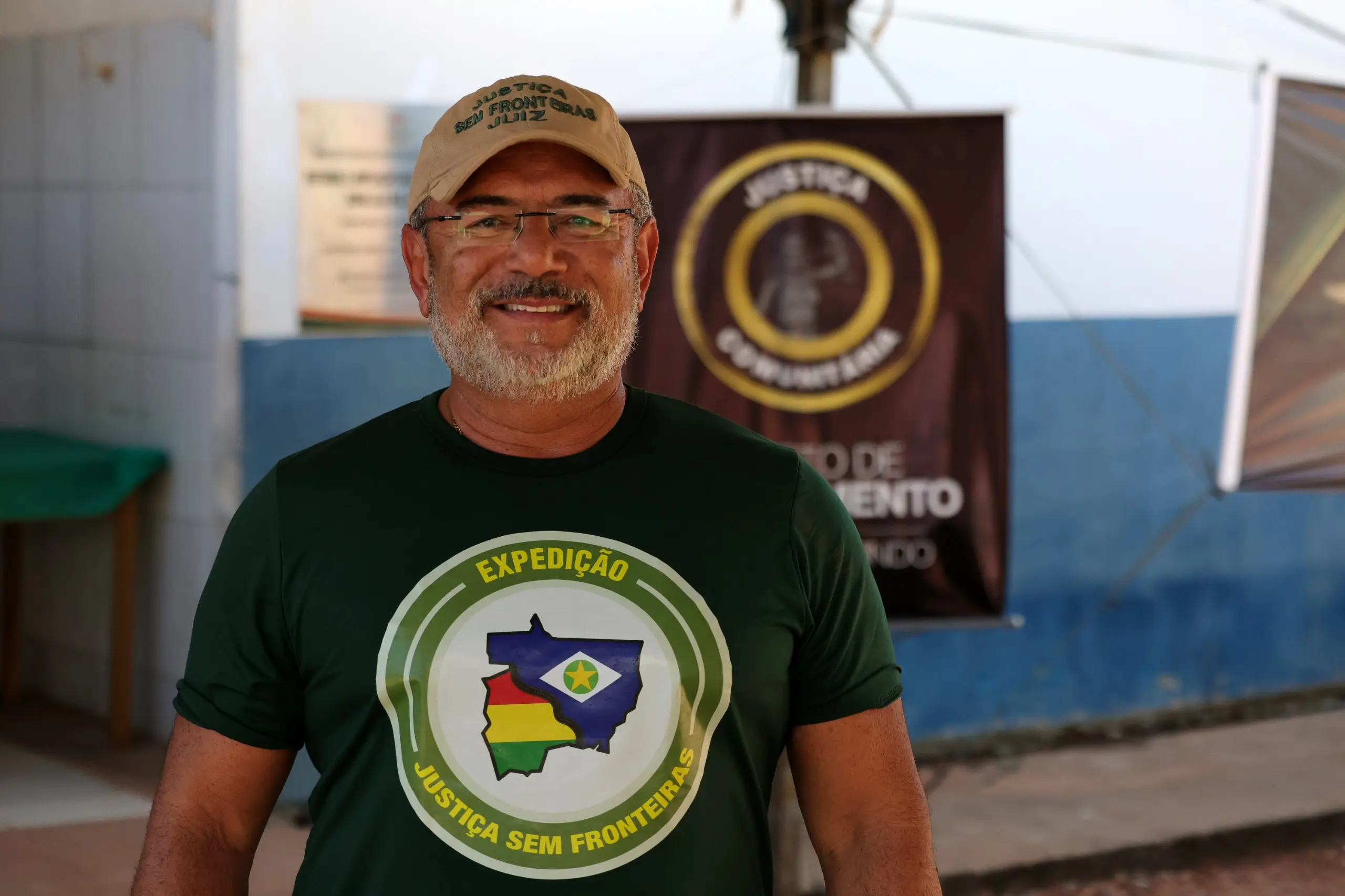 Juiz José Antônio Bezerra Filho é um homem de pele clara, barba branca e óculos sorri de frente. Ele usa um boné bege escrito