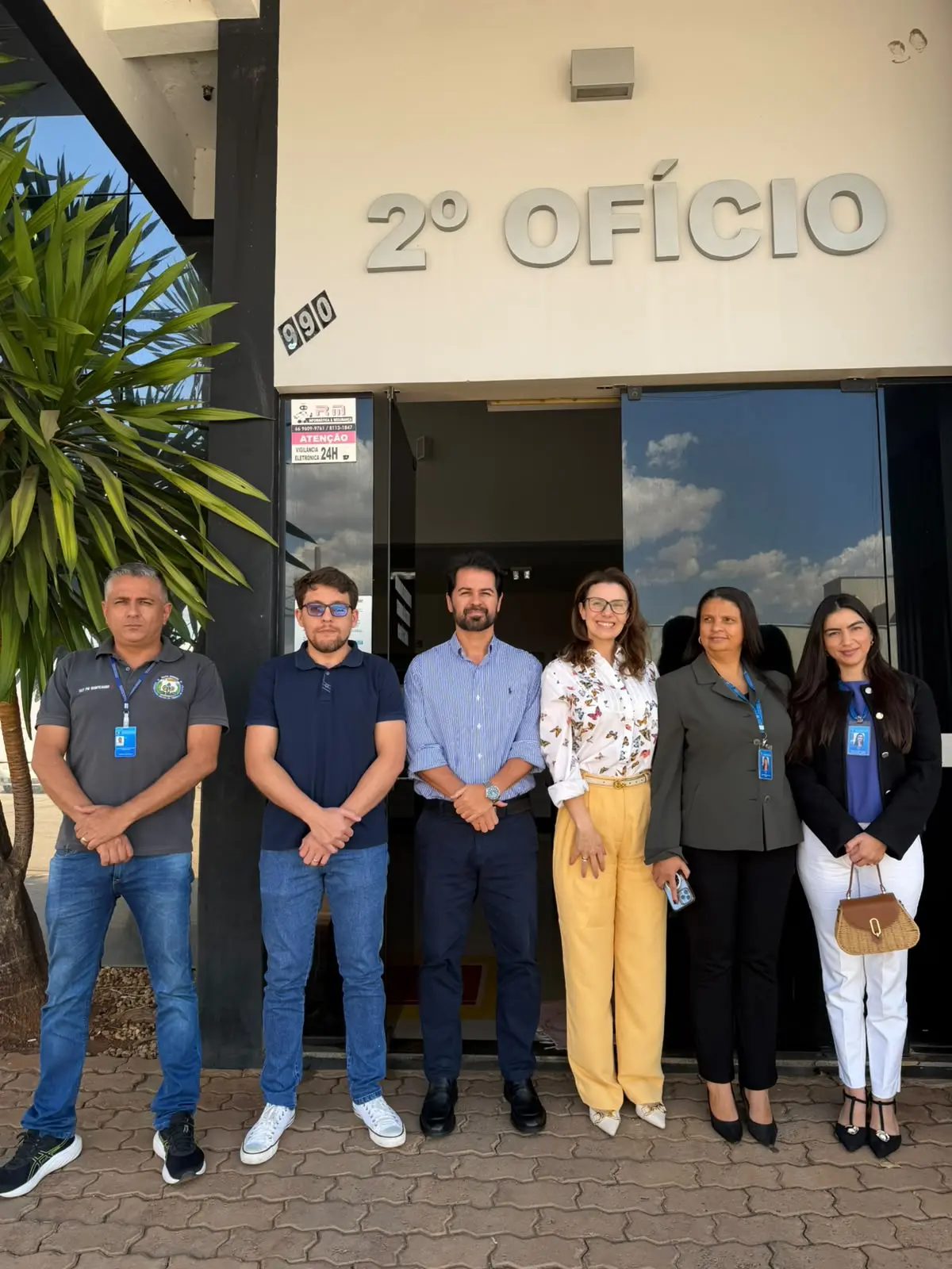 Seis pessoas estão em pé em frente ao Cartório do 2º Ofício de Jaciara. Ao centro estão o cartorário Marcelo Farias Machado e a juíza auxiliar da Corregedoria Myrian Pavan Schenkel. Na fachada, aparece a identificação 